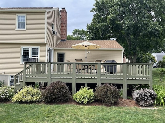 back of property with a chimney, a lawn, and a wooden deck