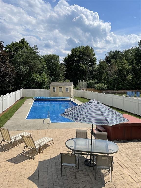 view of pool with a fenced in pool, an outbuilding, a patio, outdoor dining space, and a fenced backyard