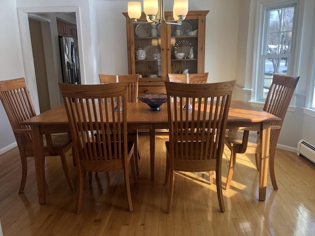 dining space featuring light wood-type flooring, baseboards, and a chandelier