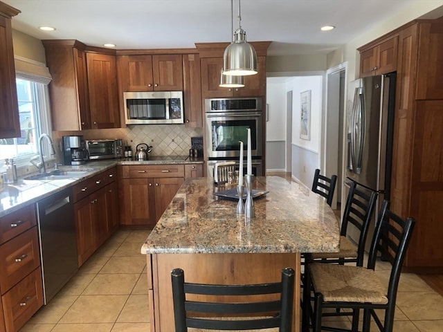 kitchen featuring a breakfast bar area, stainless steel appliances, hanging light fixtures, decorative backsplash, and a kitchen island