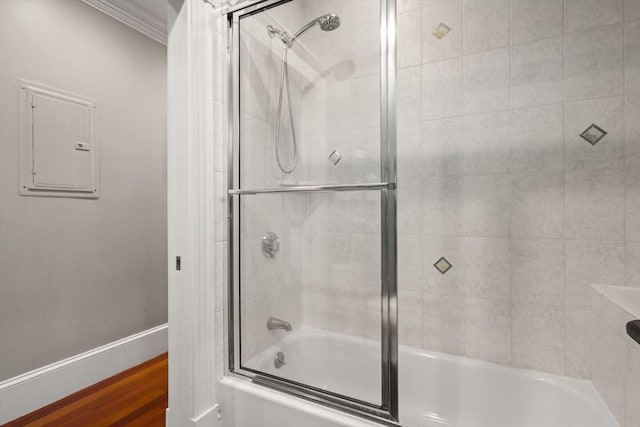 bathroom with electric panel, combined bath / shower with glass door, baseboards, and ornamental molding