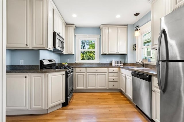 33 Lowell Ave, Watertown, MA 02472 - kitchen with appliances with stainless steel finishes, dark countertops, pendant lighting, a sink, and light wood-style floors
