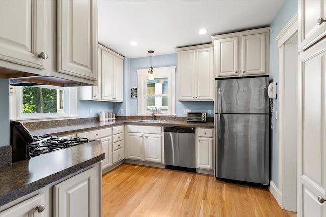 33 Lowell Ave, Watertown, MA 02472 - kitchen featuring stainless steel appliances, a sink, dark countertops, light wood-style floors, and recessed lighting