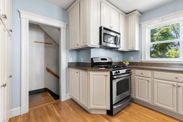 33 Lowell Ave, Watertown, MA 02472 - kitchen featuring appliances with stainless steel finishes, light wood-style floors, white cabinetry, and baseboards