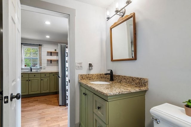 bathroom featuring wood finished floors, vanity, toilet, and recessed lighting