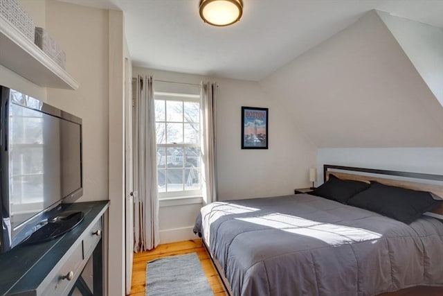 bedroom with vaulted ceiling and light hardwood / wood-style floors