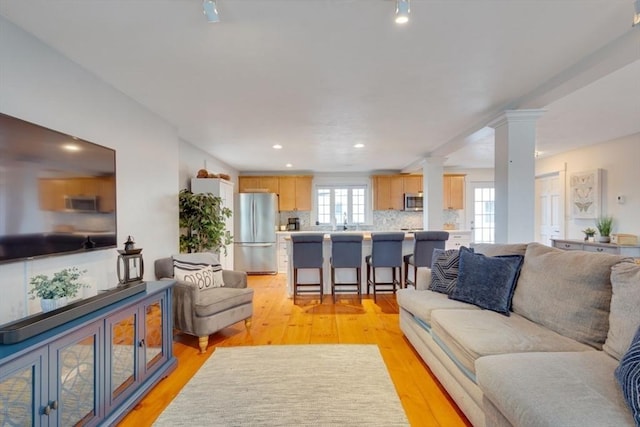 living room with decorative columns and light hardwood / wood-style flooring