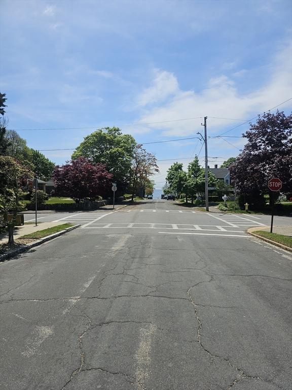 view of asphalt road with traffic signs, curbs, sidewalks, and street lights