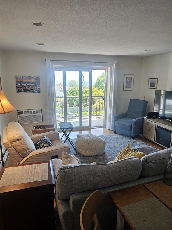 living area featuring an AC wall unit and a textured ceiling
