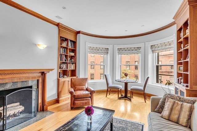 living area with hardwood / wood-style floors, a high end fireplace, and ornamental molding