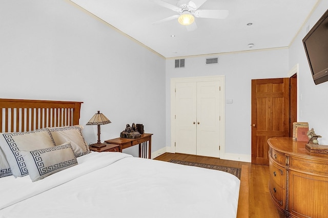 bedroom with a closet, wood-type flooring, ornamental molding, and ceiling fan