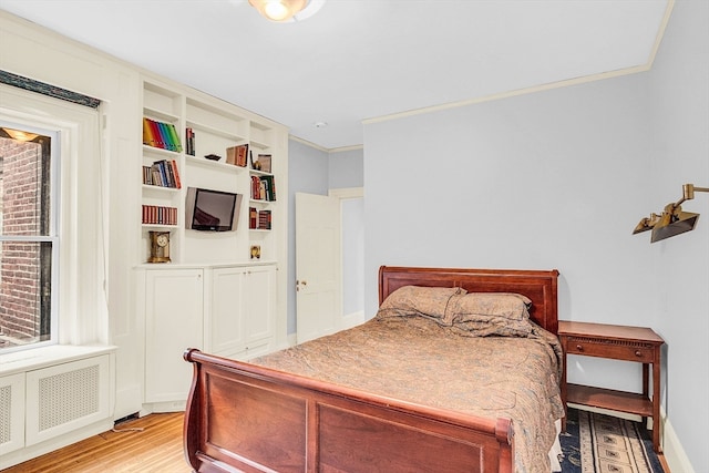 bedroom featuring radiator heating unit, ornamental molding, and light hardwood / wood-style floors