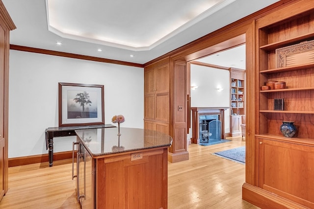 interior space with light hardwood / wood-style floors, a high end fireplace, crown molding, and dark stone counters