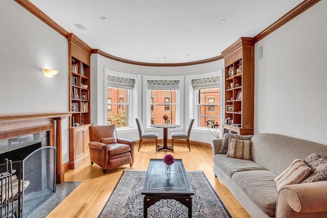 interior space featuring built in features, a premium fireplace, ornamental molding, and light wood-type flooring