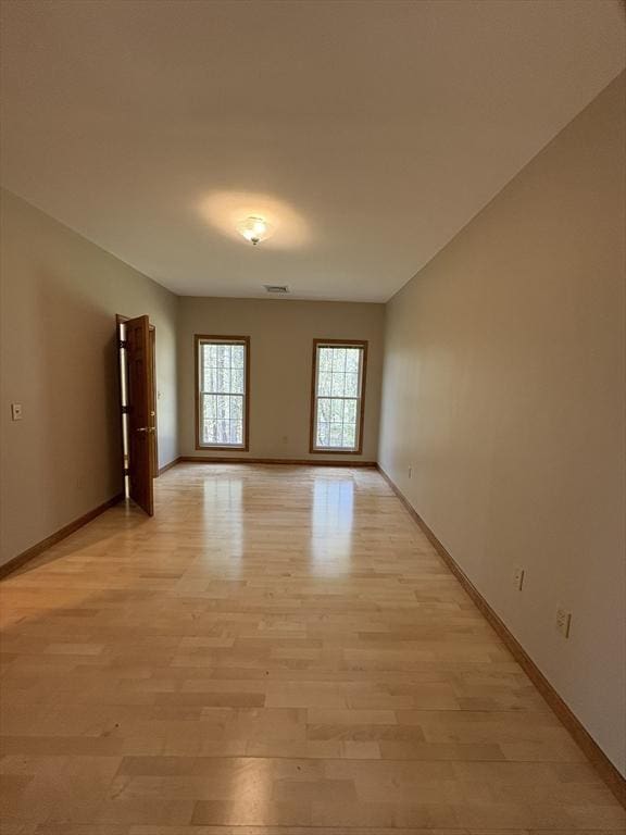 spare room featuring baseboards, light wood-style flooring, and visible vents