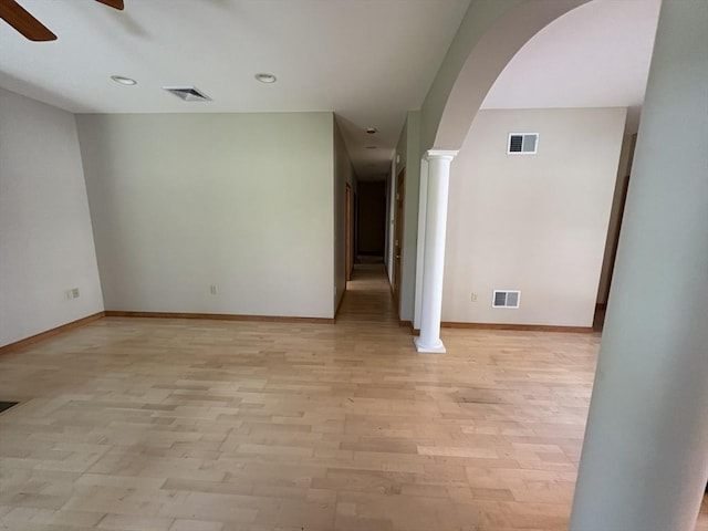 empty room featuring visible vents, a ceiling fan, and arched walkways