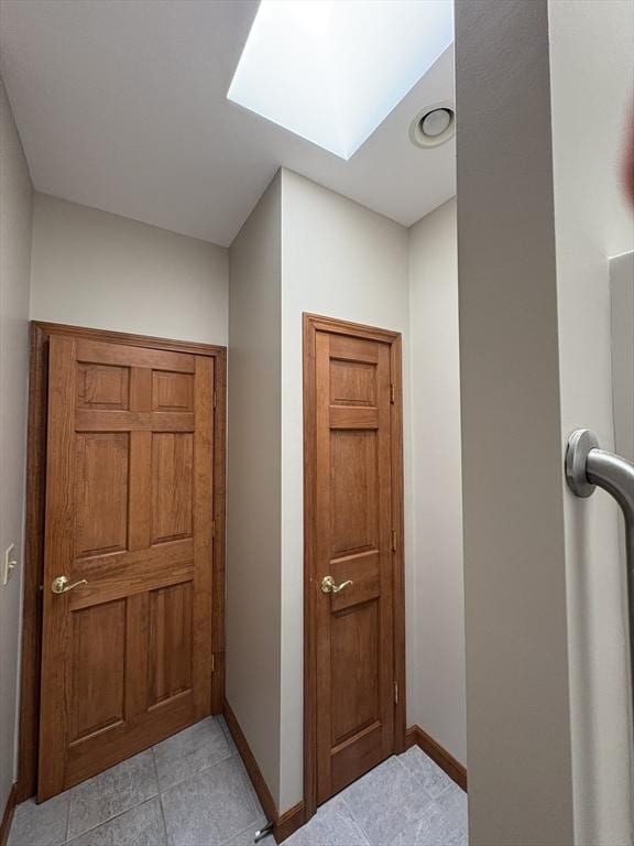 hall with a skylight and baseboards