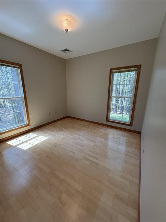 unfurnished room with visible vents, baseboards, a healthy amount of sunlight, and light wood-type flooring
