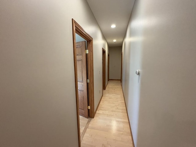 corridor with baseboards, recessed lighting, and light wood-style flooring