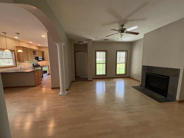 living room with baseboards, a fireplace, a ceiling fan, and a wealth of natural light