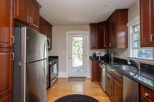 kitchen featuring stainless steel appliances, dark stone countertops, a wealth of natural light, and sink