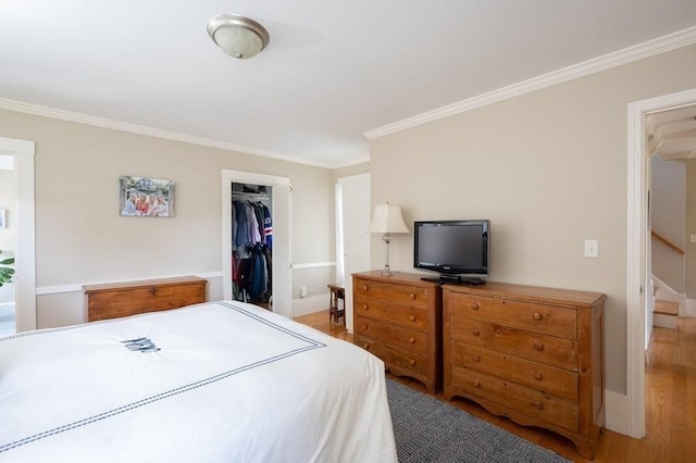 bedroom with ornamental molding, a spacious closet, hardwood / wood-style floors, and a closet