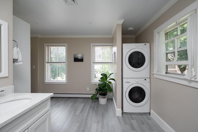 laundry area featuring stacked washer and clothes dryer, a wealth of natural light, and crown molding