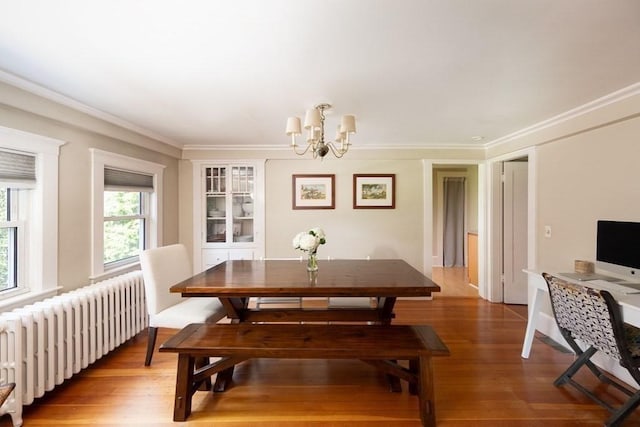 dining area featuring crown molding, wood-type flooring, radiator, and a chandelier