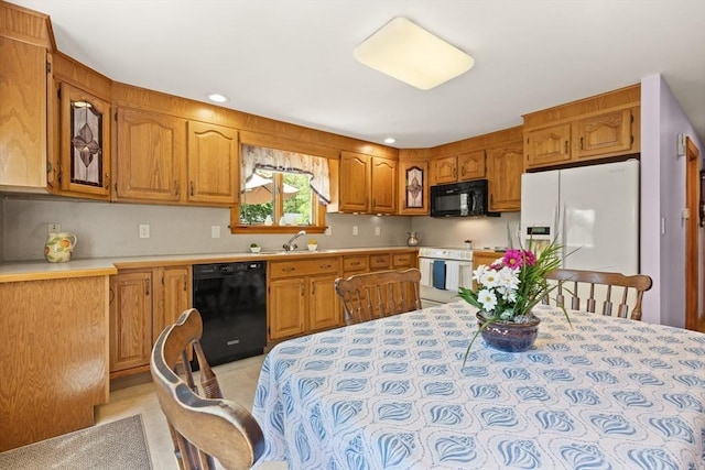 kitchen featuring black appliances, a sink, brown cabinets, light countertops, and recessed lighting