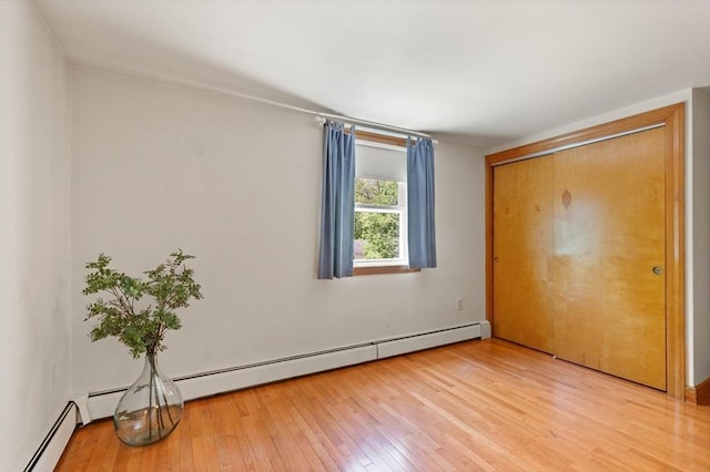 unfurnished bedroom featuring light wood-style floors and a baseboard radiator