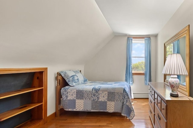bedroom with a baseboard heating unit, wood finished floors, lofted ceiling, and baseboards