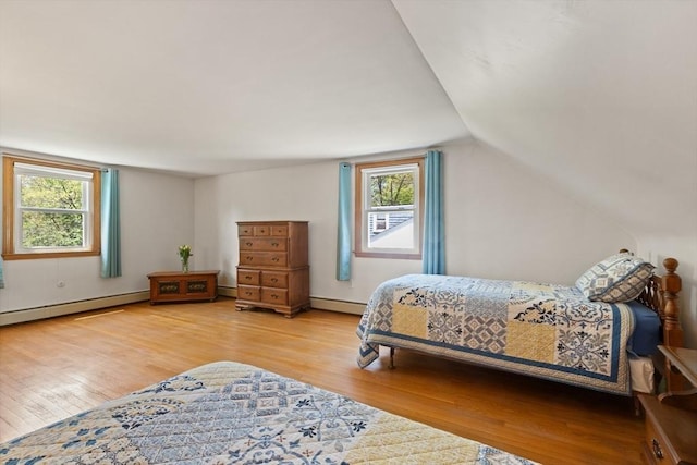 bedroom with multiple windows, a baseboard radiator, wood finished floors, and lofted ceiling