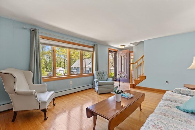 living area featuring baseboard heating, stairway, wood finished floors, and baseboards