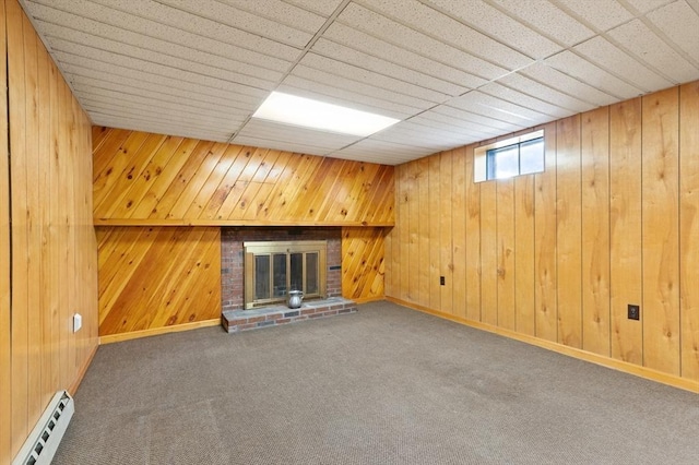 unfurnished living room featuring a baseboard radiator, a fireplace, wood walls, carpet, and baseboards