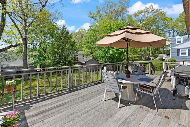 wooden deck with outdoor dining space, a storage unit, and an outbuilding