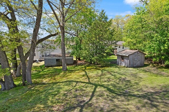 view of grassy yard with a storage shed and an outdoor structure