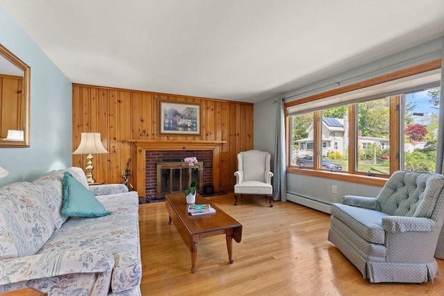 living area with a baseboard radiator, light wood-type flooring, wooden walls, and a fireplace