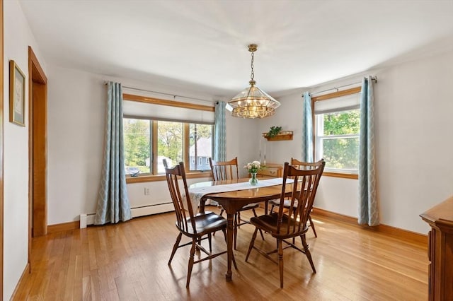 dining area with light wood-style flooring, a chandelier, baseboards, and a baseboard radiator