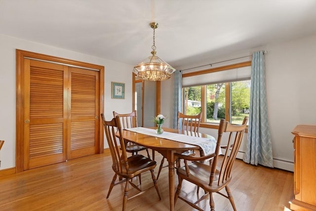 dining space featuring a chandelier, light wood finished floors, and a baseboard heating unit