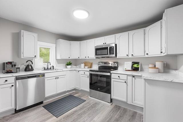 136 Locust Way, Winthrop, MA 02152 - kitchen with appliances with stainless steel finishes, a sink, white cabinets, and light wood-style floors