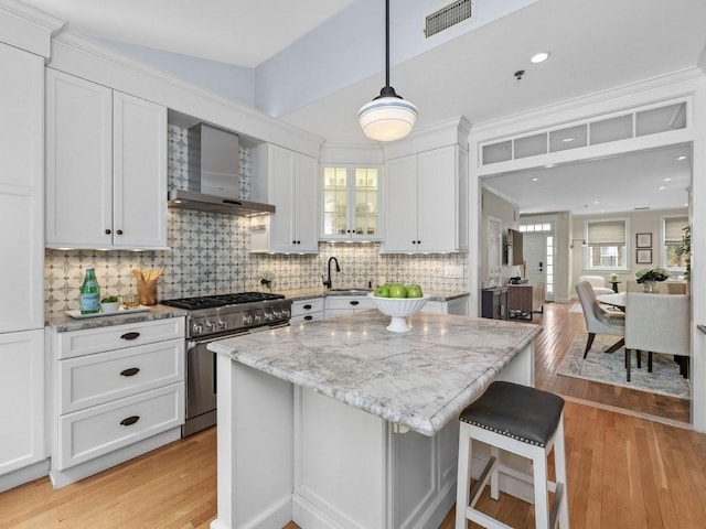 92 Warren St Unit W-1, Boston, MA 02129 - kitchen featuring stainless steel stove, wall chimney range hood, light wood-style floors, a sink, and white cabinets