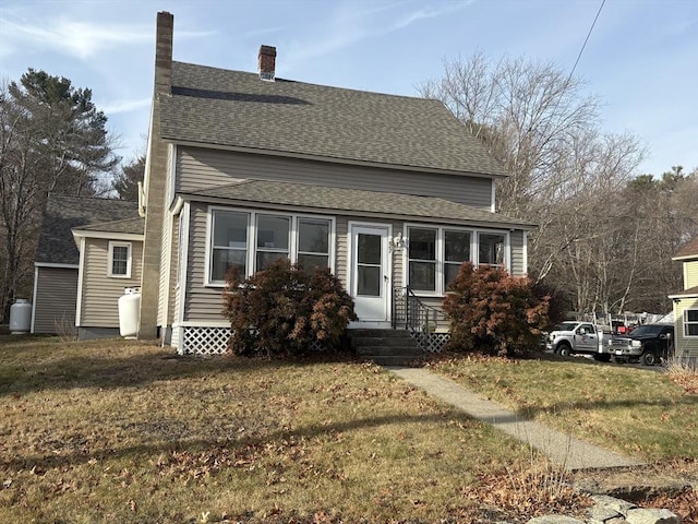 view of front of home featuring entry steps, a front lawn, and a shingled roof