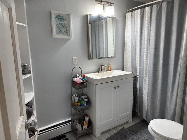 bathroom featuring toilet, a baseboard heating unit, and vanity