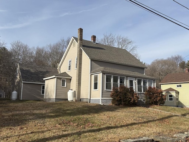 view of side of property with roof with shingles, a yard, and a chimney