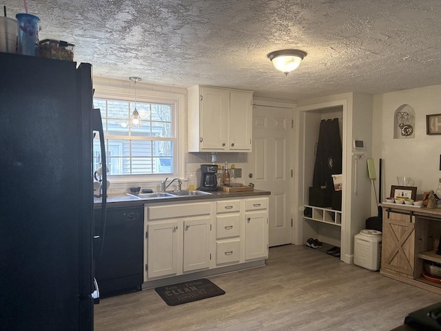 kitchen with black appliances, a sink, white cabinetry, and light wood-style floors