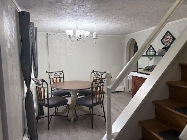 dining room featuring crown molding, an inviting chandelier, a textured ceiling, wood finished floors, and stairs