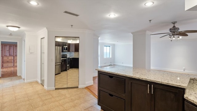 kitchen with stainless steel appliances, light stone counters, crown molding, light tile patterned floors, and ceiling fan