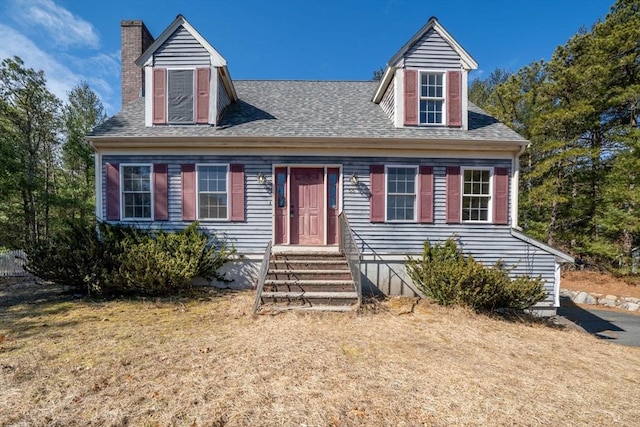 cape cod home featuring entry steps, roof with shingles, and a chimney