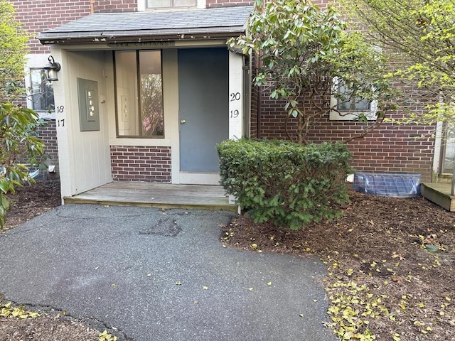 property entrance with brick siding and a shingled roof