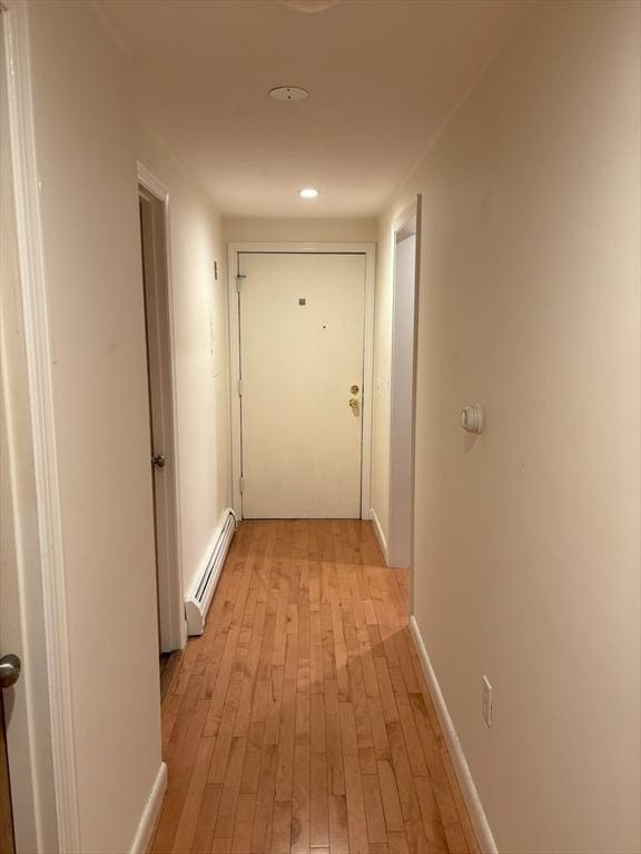 corridor featuring light wood-style floors, baseboards, baseboard heating, and recessed lighting